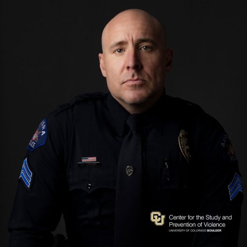 Headshot of a white bald man wearing a navy police uniform.